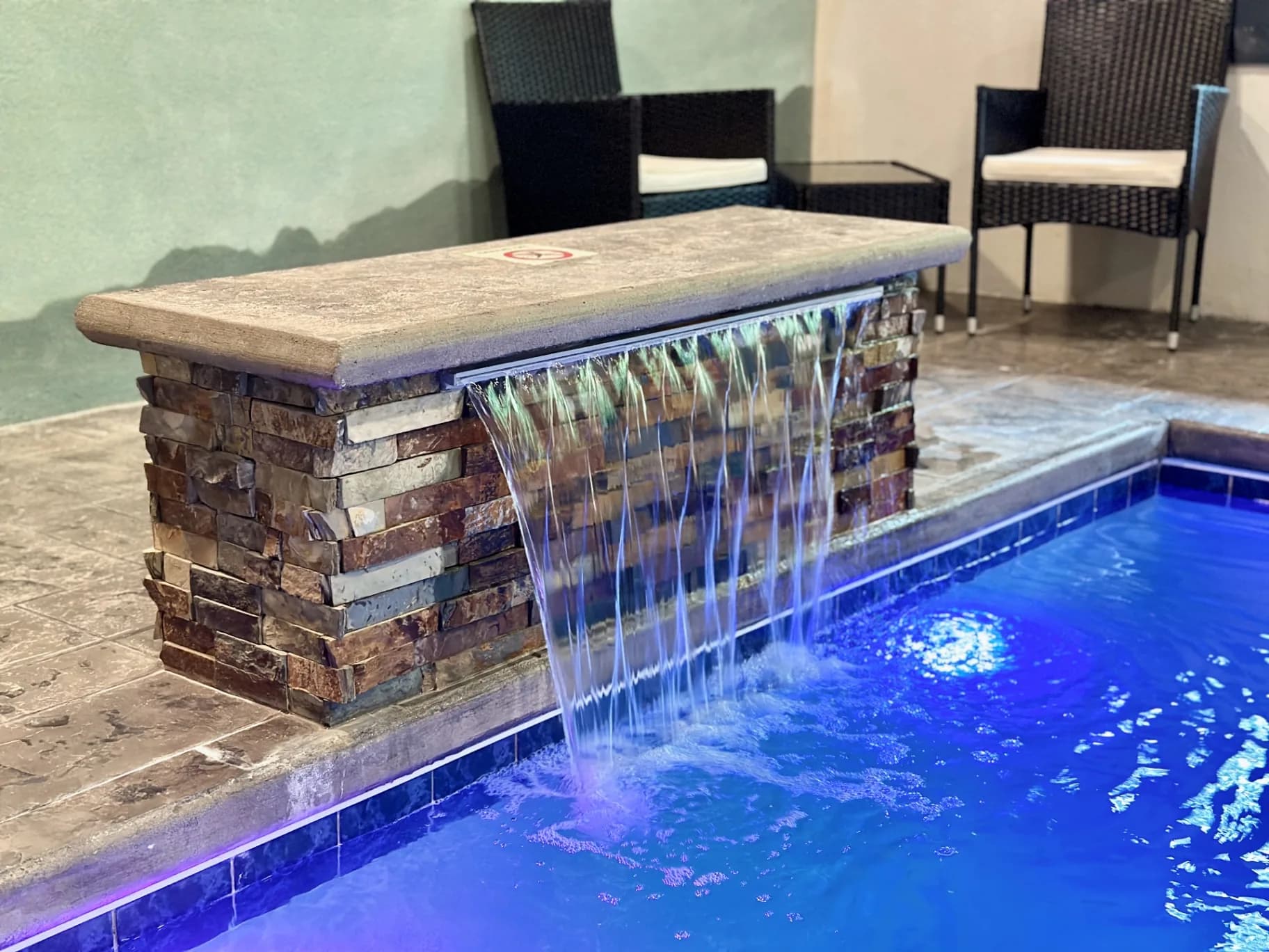 Stone waterfall feature in the private indoor pool at Whispering Pines Lodge